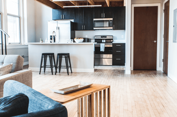 A modern kitchen with a blue chair and a wooden table.